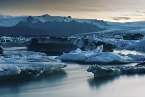 Icebergs and a calm glacial lake at dusk
