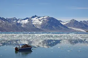 Icebergs reflected in a fjord, small blue boat