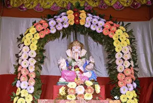 Idol of Lord Ganesh kept in gaily decorated frame of colourful flowers elephant headed god