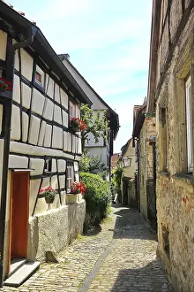 Idyllic cobblestone street with flower-decorated half-timbered houses in Bad Wimpfen