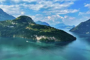 An idyllic lake with blue water, surrounded by mountains under a cloudy sky, crossed by a boat, Morschach, Switzerland, Europe