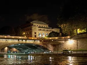 Illuminated historical building and bridge with reflected light in the water