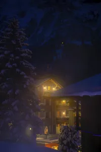 Illuminated House and Mountain in a Snowy Winter Night in Grindelwald
