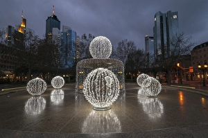 Illuminated Lucae Fountain on Opernplatz square in front of high-rise skyline