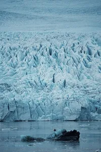 Imposing glacier with intricate ice formations reflecting in tranquil water