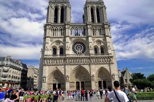 The imposing front of Notre-Dame Cathedral surrounded by numerous people admiring the historic building