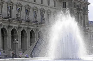Impressive fountain in front of the classical facade of the Louvre with sculptures