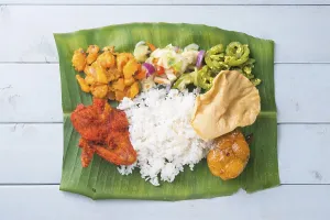 Indian banana leaf rice, overhead view on wooden dining table