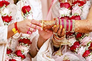 Indian groom passing bangles on his brides hand on her wedding ceremony