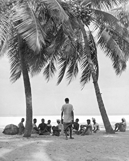 Indian people sitting below palm tree at Allepy, Kerala, India 1940's