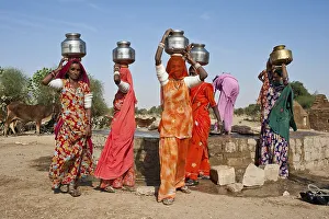 Indian women wearing saris carrying water jugs on their heads