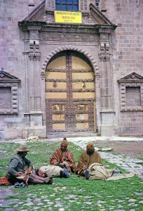 Three indigenous men sitting in front of a historic Spanish colonial building, Cuzco, Peru, South America 1962, South America