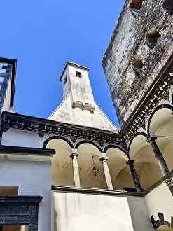 Inner courtyard with columns and tower under a clear blue sky