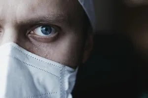 Intense close-up of a masked doctor focusing with piercing blue eyes
