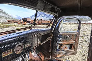 Interior view of a rusty car in front of steep mountains