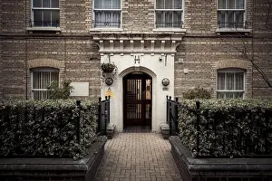 Framed Print : An inviting residential entrance with brick architecture and lush greenery in London Framed Print : An inviting residential entrance with brick architecture and lush greenery in London