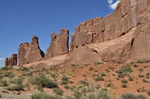 Jagged sandstone formations called Wall Street and sparse vegetation stretch under a clear sky in the desert