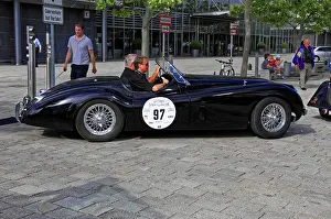 JAGUAR XK 120, black classic roadster with two men on a paved road