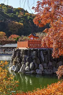 Japanese temple in autumn with bright red leaves and reflection in calm water