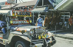 Jeepney minibus in front of a restaurant with skewered suckling pig