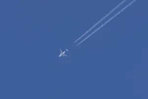 Jet passenger aircraft with a vapour trail or contrail flying in a blue sky