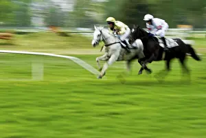 Two jockeys racing on a grassy field