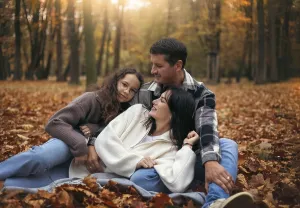 A joyful family relaxes in a forest amidst colorful autumn leaves