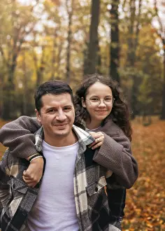 A joyful father and daughter embrace in an autumn forest