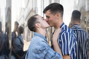 A joyful gay couple shares a tender kiss on the lively streets of Madrid