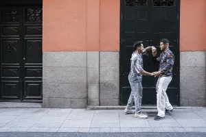 A joyful latin gay couple shares a moment of affection on a lively street in Madrid