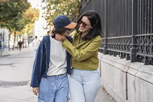 A joyful lesbian couple shares a loving moment while walking along a city street