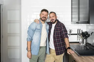 A joyful, loving gay couple stands in their modern kitchen