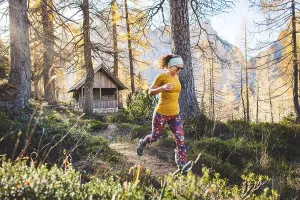Joyful woman hiker running in the autumn forest
