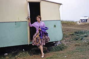 Junge Frau mit Tennisschlaeger, die aus einem Wohnwagen auf einem Wohnwagenplatz aussteigt, England, UK, 1961