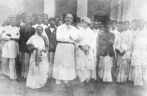 Kasturba and Mahatma Gandhi together with a priest shortly after their return to India, 1915