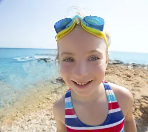 Kid funny girl wide angle beach portrait with swimsuit and swimming goggles