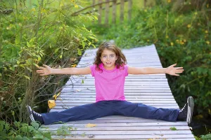 Kid girl in autumn deck smiling with braces open arms and legs outdoor