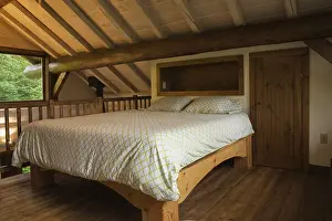 King size bed with pine wood frame in sparsely furnished Zen stmaster bedroom on mezzanine inside Scandinavian hybrid