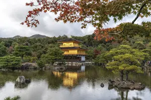 Kinkakuji golden pavilion on a small pond taken during autumn foliage season during a small rain