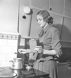 Kitchen in the 1940s. A woman is seen in the kitchen making coffee, measuring adding grinded coffee into the coffee pot. Sweden 1949. Kristoffersson ref AU82-3