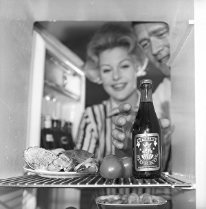 In the kitchen 1950s. A couple in their kitchen and at the refrigerator where the food and beer is kept
