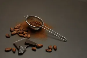 Kitchen sieve with cocoa powder and chocolate