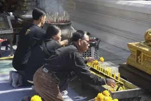 Three kneeling Buddhists with candles and incense