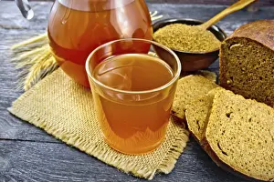 Kvass in glassful and glass jug on burlap