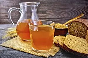 Kvass in glassful and glass jug on burlap