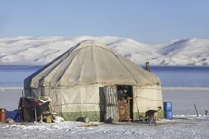 Kyrgyz man in door opening of traditional yurt in the snow along Song Kul