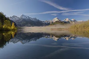 Lake Almsee in autumn with a forest and mountains reflected in the lake