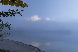 Lake Almsee in autumn with a slowly dissipating fog that moves over the lake