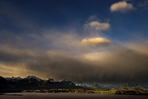 Lake Hopfensee with stormy sky in soft morning light and Allgaeu mountains in the background