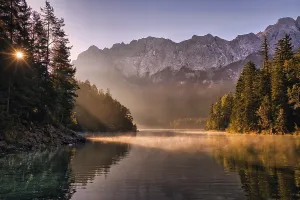 Lake at sunrise with fog, mountains and reflection